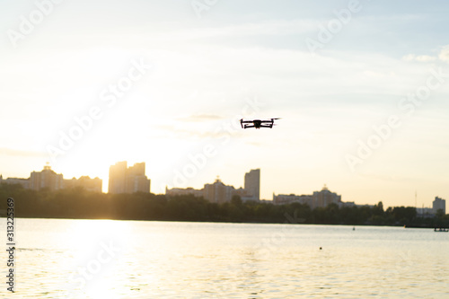 Drone flying over the river beach at the sunset with cityscape at the background