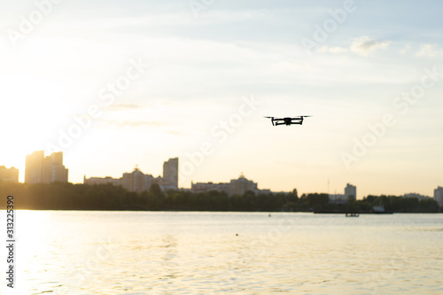 Drone flying over the river beach at the sunset with cityscape at the background