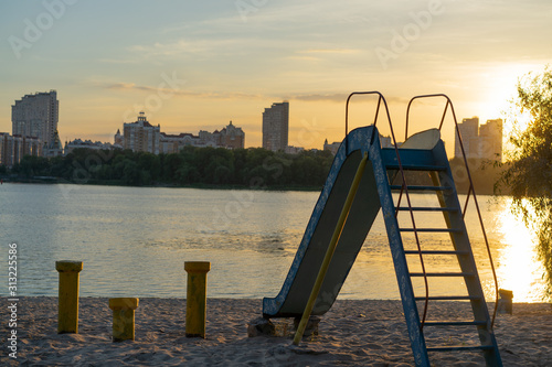 Beautiful view over the river bank at the sunset with cityscape at the background