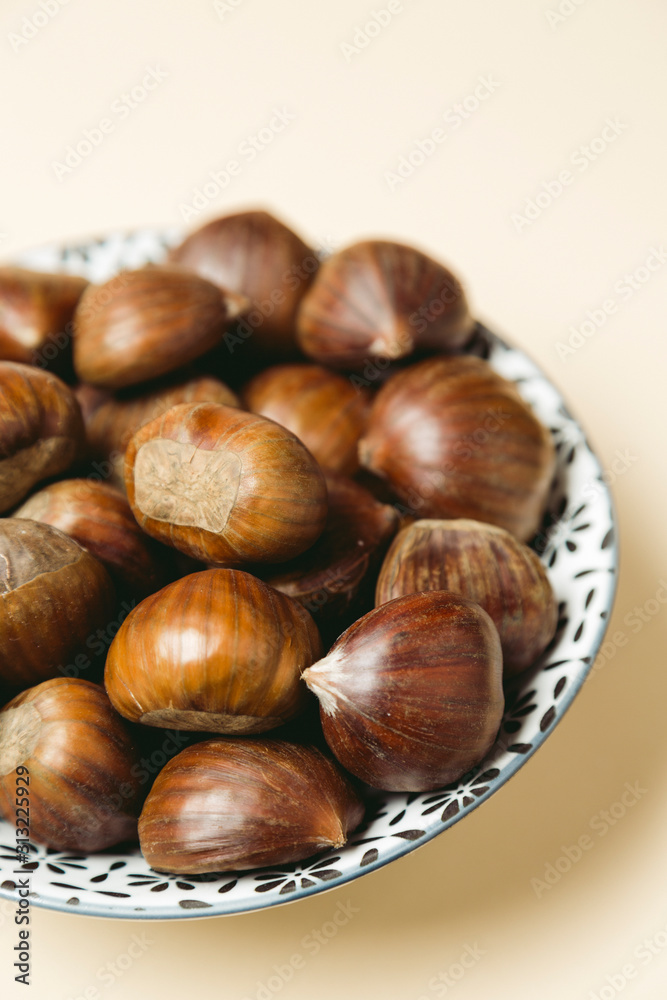 A nice bowl of chestnuts on beige background A nice bowl of chestnuts on beige background