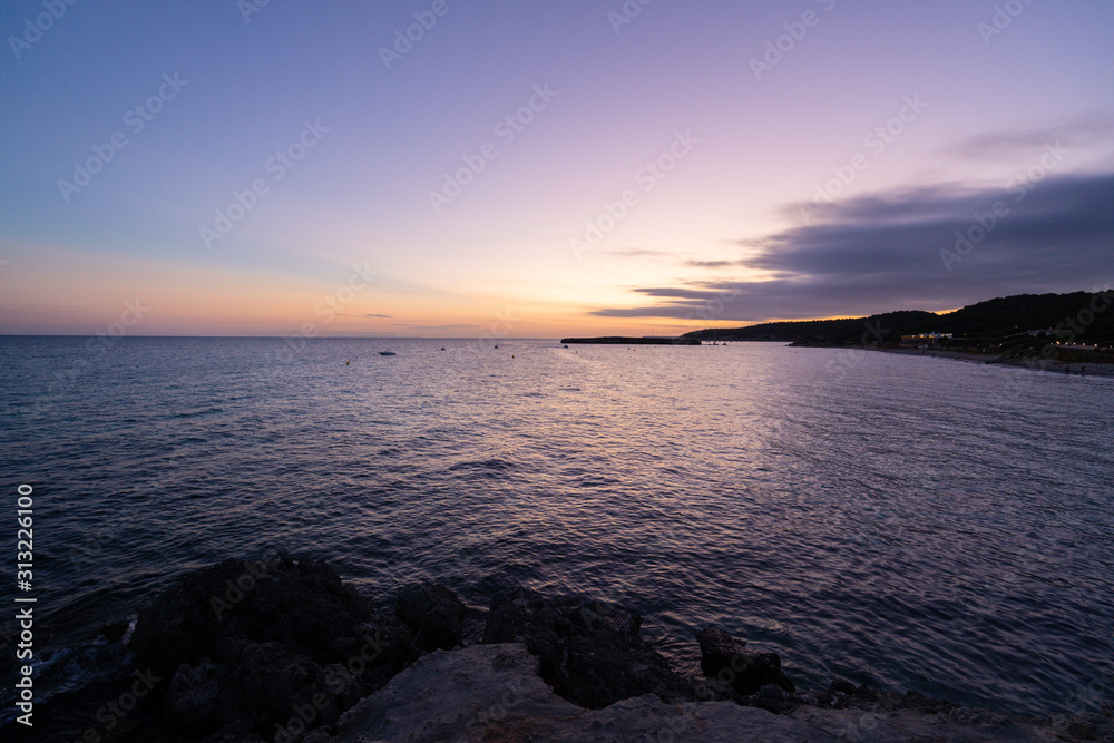 Beach of Sant Tomas on the island of Menorca during sunset. Mediterranean sea in spanish island.
