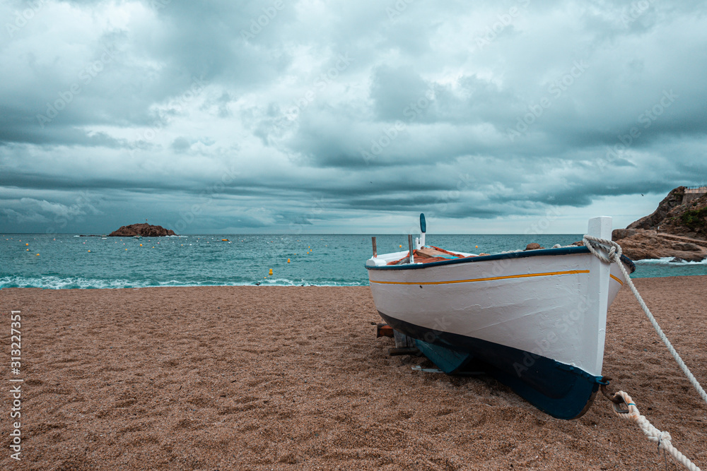 Costa Brava, Spain. Fishing boats rest on a golden sand beach overlooking the blue sea at Calella. Costa Brava, Spain. Fishing boats rest on a golden sand beach overlooking the blue sea at Calella.