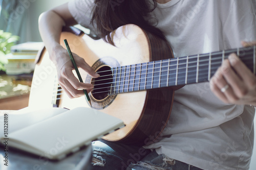 songwriter thinking and writing notes,lyrics in book at studio.man playing live acoustic guitar.concept for musician creative.artist composer in work process.people relaxing time with instrument 