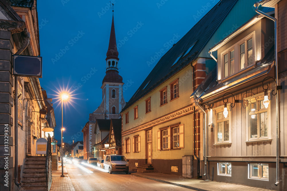 Parnu, Estonia. Night Puhavaimu Street With Old Wooden Houses, Restaurants, Cafe, Hotels And Shops In Evening Night Illuminations. View Of Lutheran Church Of St. Elizabeth