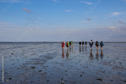  hiking along the bottom of the sea is completely mud at low tide. Traces of tourists feet in the mud at the bottom of the North Sea. photo