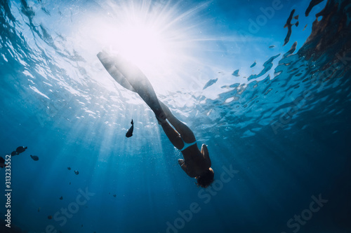 Woman freediver relax with fins underwater. Freediving girl and beautiful light in blue sea