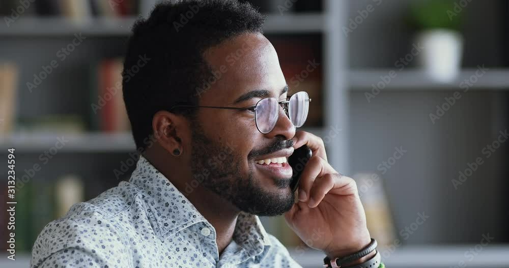 Smiling afro american businessman talking on phone in office, closeup
