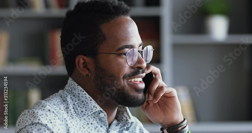 Smiling afro american businessman talking on phone in office, closeup