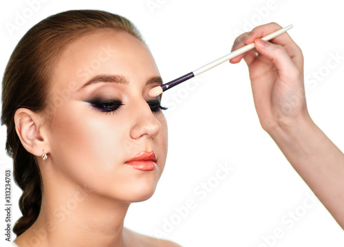 Makeup artist paints the eyes of a woman client shadows on a brush