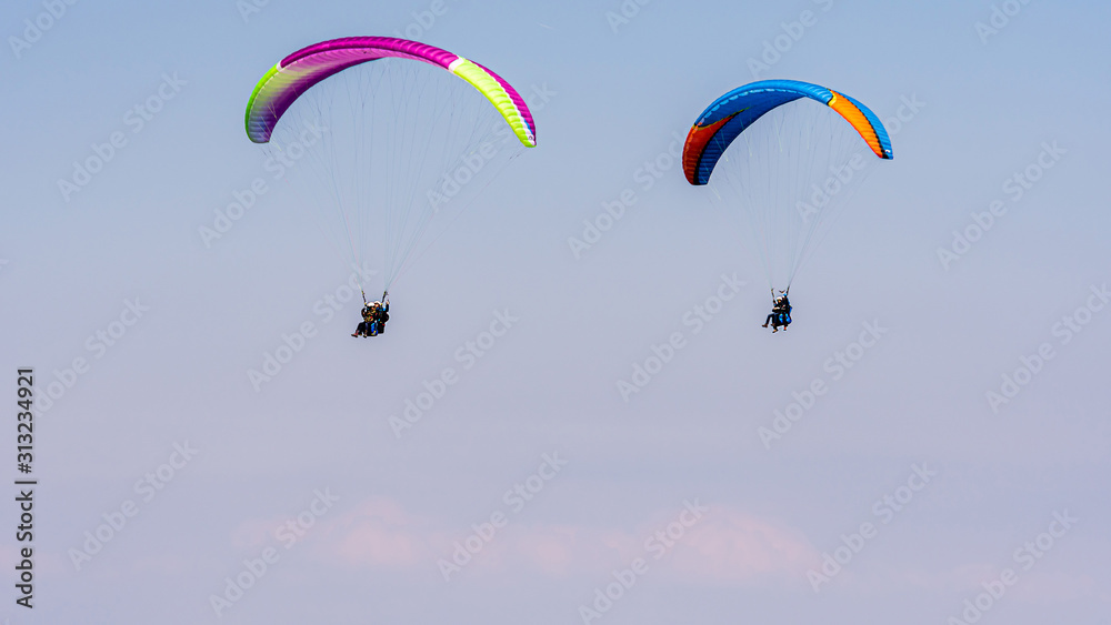 Paragliding in Swiss Alps over the mountains against clear blue sky Paragliding in Swiss Alps over the mountains against clear blue sky