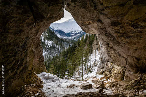 Fototapeta Naklejka Na Ścianę i Meble -  Hole (Pawlikowski's Window) in the Mylna Cave (False Cave) in the Koscieliska Valley in the Western Tatras, with a view of the winter landscape of the mountains, Poland.