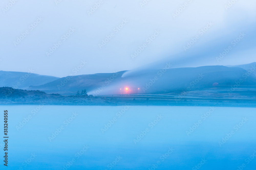 Geothermal powerplant at the blue lagoon in Jarabodin/Myvatn in Iceland during blue hour. Long exposure shot of steam smoke and azure blue lake. Traveling concept.