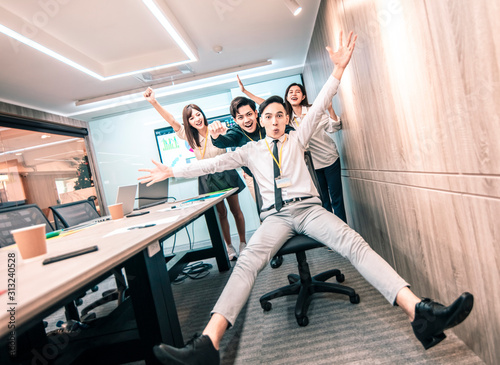 business people having fun riding on chairs in office