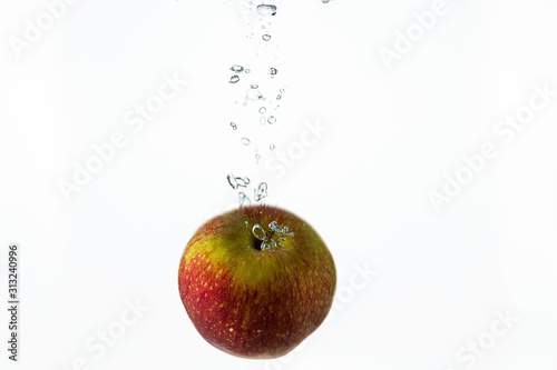 Close up view splashing water and red apple on white background. Beautiful backgrounds.