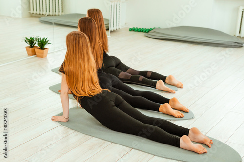 Stretching workout. A group of young girls in black uniforms are doing stretching training in the gym. Akroyoga, yoga, fitness, workout. photo