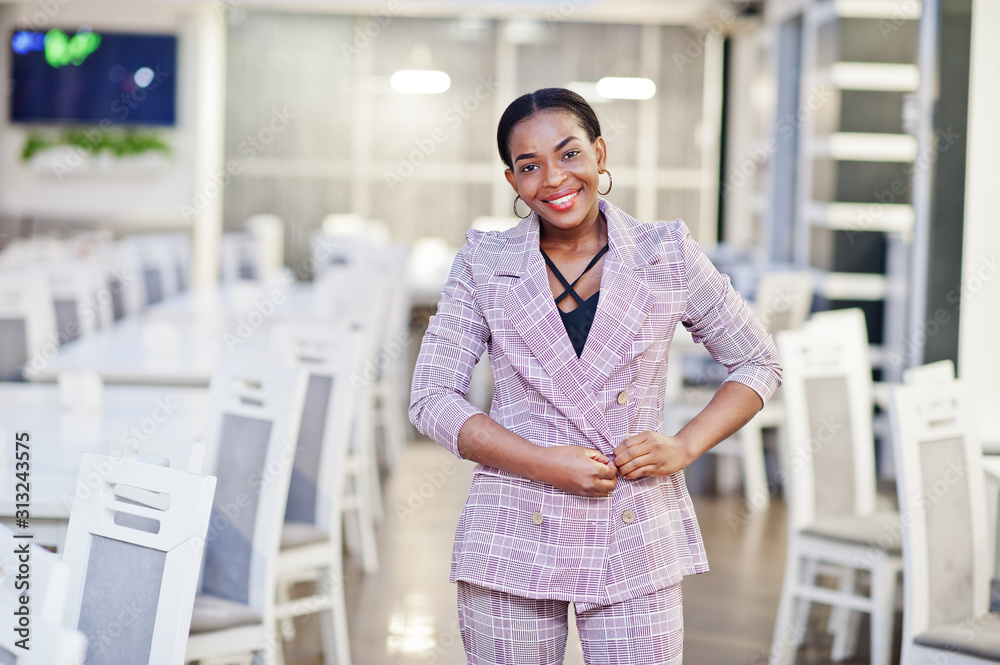 Charming african american woman in jacket posing at restaurant.