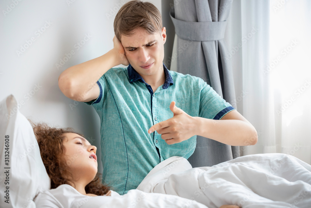 Caucasian couple in pajamas snoring and bad sleeping on the bedroom.His blocking ears with hands. Caucasian couple in pajamas snoring and bad sleeping on the bedroom.His blocking ears with hands.