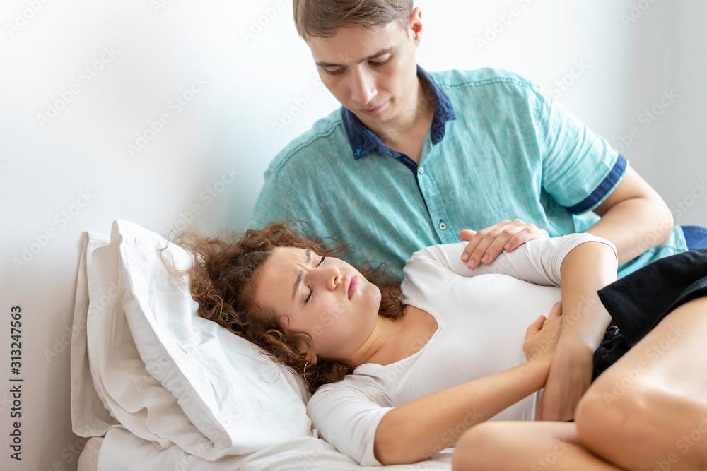 Boyfriend take care girlfriend.Young Caucasian woman patient with period  pain on bed room. Stock Photo | Adobe Stock