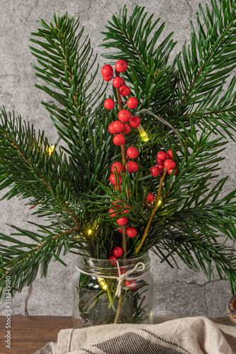 Christmas decoration with pine branches in a jar, lights and red holly balls.  Christmas tree wallpaper for card or other design in Christmas concept.