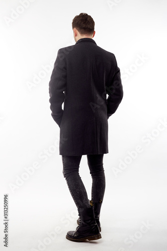 Handsome man in black winter coat, black jeans and boots isolated on white background.
