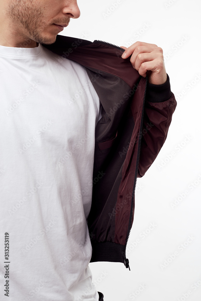 Young european man in white sweater and black pants, red bomber jacket posing on white background. Isolated. Young european man in white sweater and black pants, red bomber jacket posing on white background. Isolated.