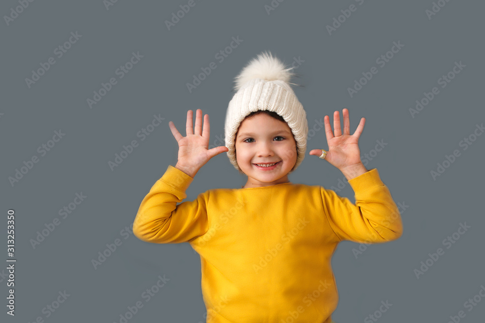 Funny caucasian child in yellow and hat on gray Funny caucasian child in yellow and hat on gray