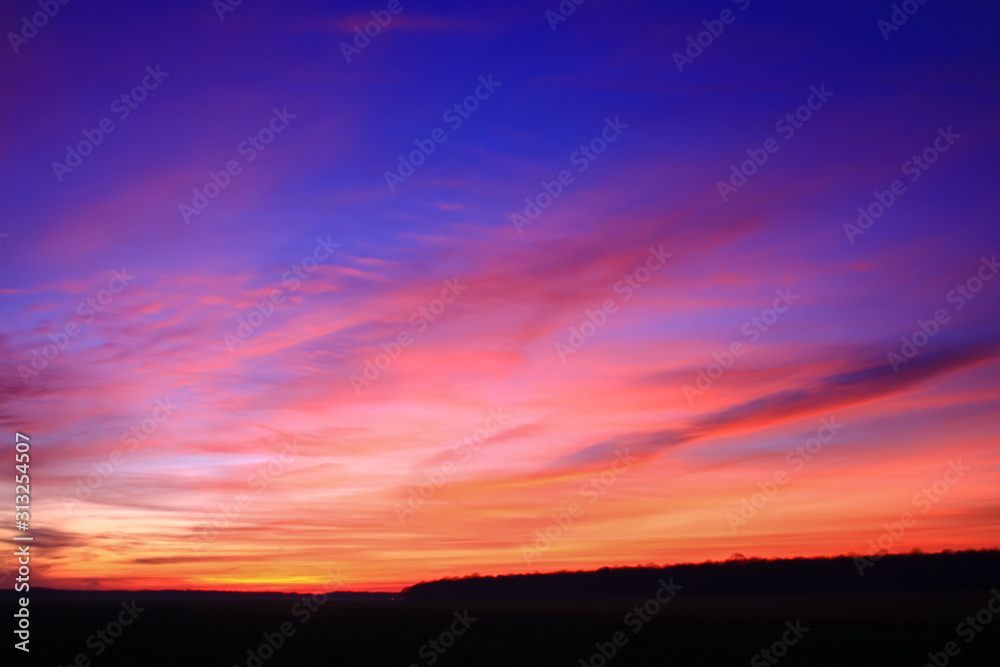 Very colorful clouds in dramatic sky. Romantic sunset at the countryside.