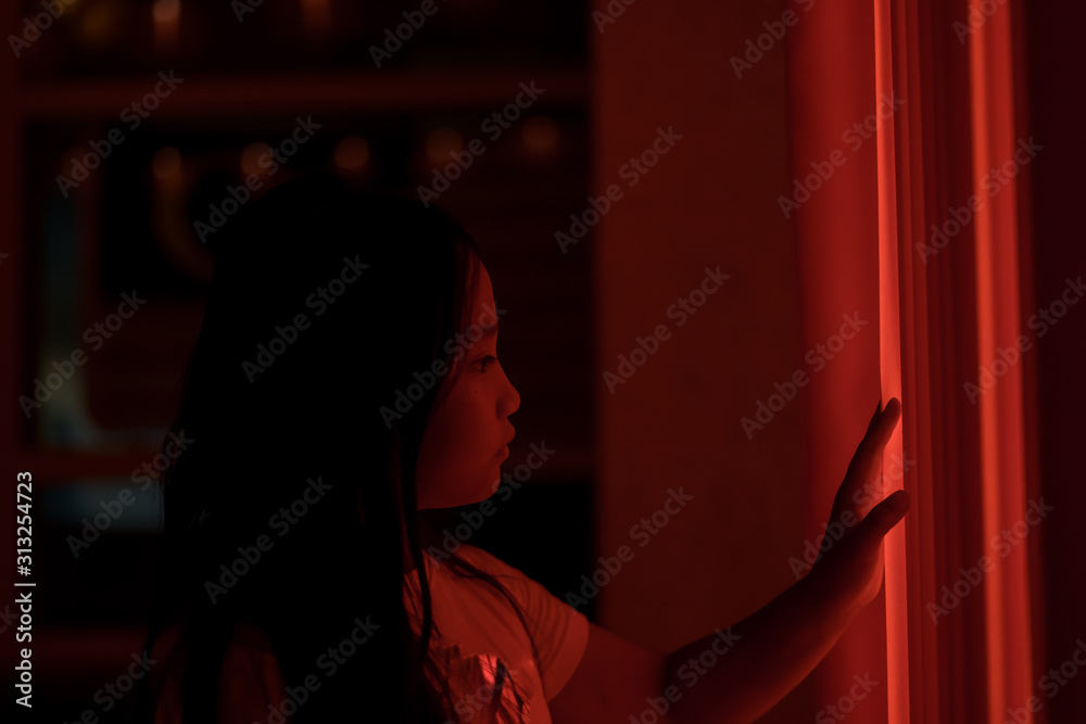 Cinematic night portrait of a little girl and red neon light.