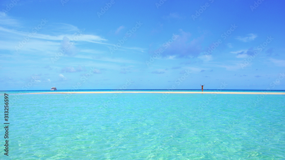 Girl standing on a sandbank surrounded by crystal clear turquoise waters at Rasdhoo atoll, Maldives