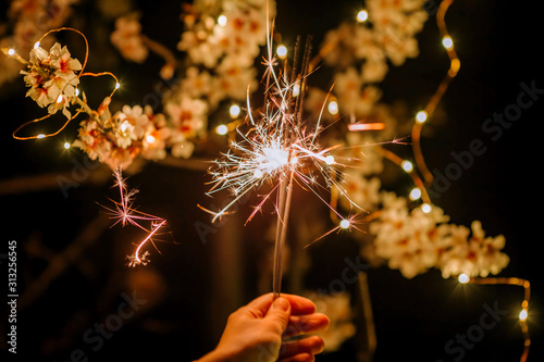 Sparkler as a symbol of the new year on the background of blossoming almonds.