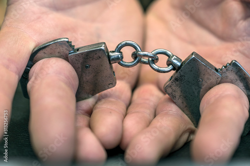close up of handcuffs for fingers on dirty male hands.