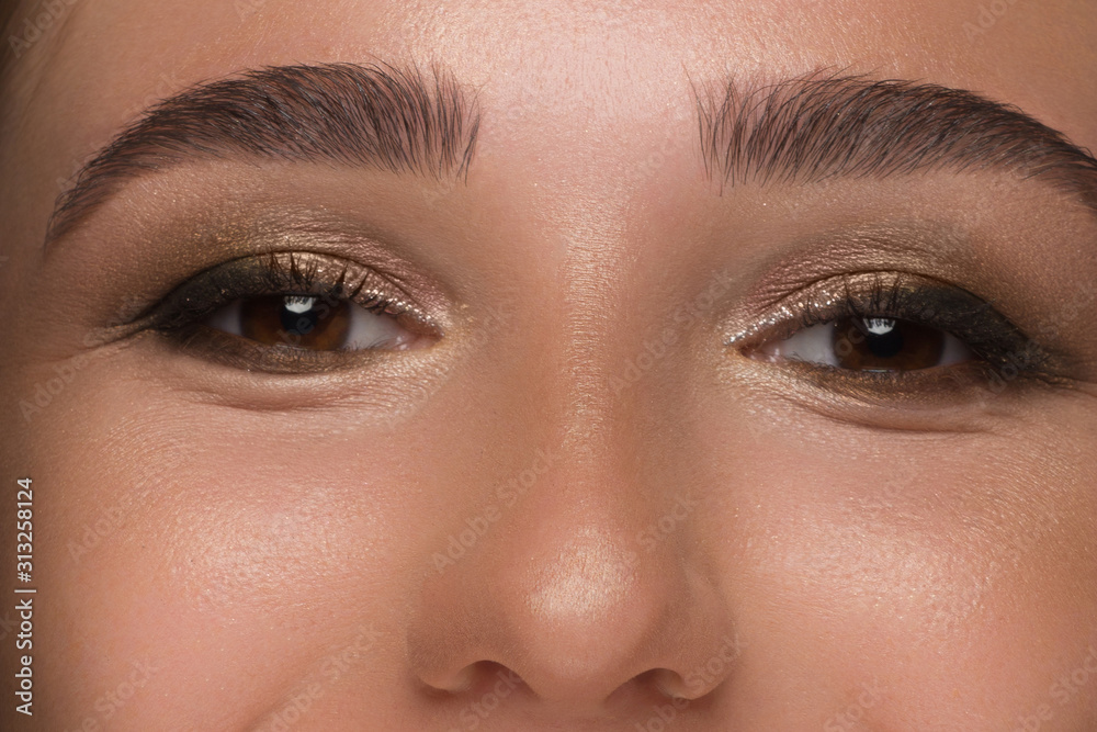 Fototapeta premium Close-up of woman's eyes with evening make-up. Fashionable shades of eye shadow, extremely long eyelashes and thick smooth eyebrows. Open beautiful look. Clean skin and freckles on face