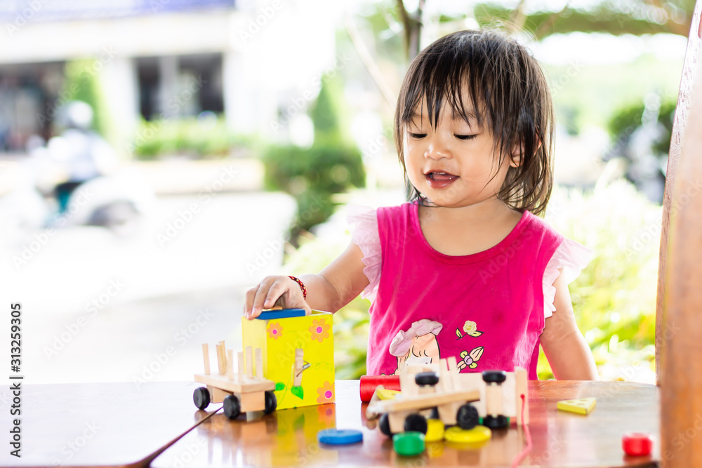 Portrait image of Asian baby girl playing the wooden block toys. On wooden table. 1-2 years old of child. Learning and development of kid concept. With copy space. Portrait image of Asian baby girl playing the wooden block toys. On wooden table. 1-2 years old of child. Learning and development of kid concept. With copy space.