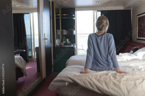 Female teenager enjoying watching sunrise from cabin luxury cruise ship. The concept of meeting the dawn on a cruise ship. Travel, sea, cruise