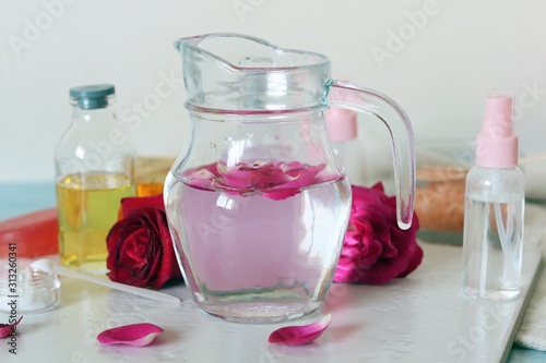 Fresh roses, petals, water and oil on the table for the preparation of natural cosmetics, spa treatments, healthy lifestyle