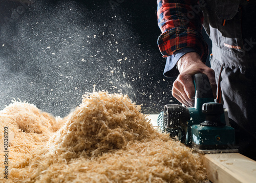 Photos Planing wooden plank with a electric plane.