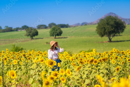 Young woman in the sunflowers field and grass field on background of the blue sky