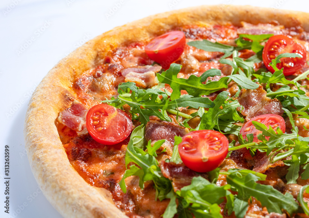 Italian hot pizza with tomato, arugula and pieces of bасon isolated on white background Italian hot pizza with tomato, arugula and pieces of bасon isolated on white background