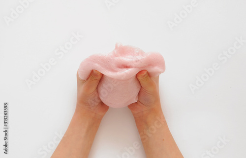 Child hands with pink slime on background.