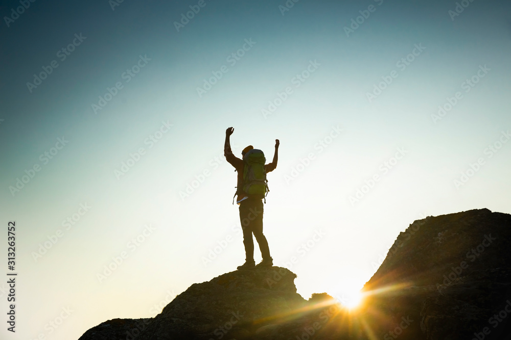 Man with arms raised at sunset