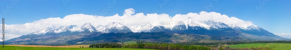 panorama of high tatas mountain ridge in spring. wonderful landscape of slovakia with snow capped peaks. clouds on the blue sky above the massif