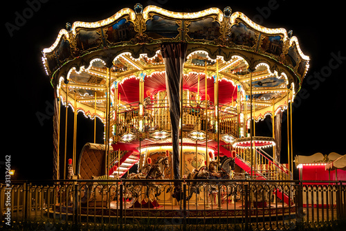 Illuminated classical carousel at night on a street of Gdansk city