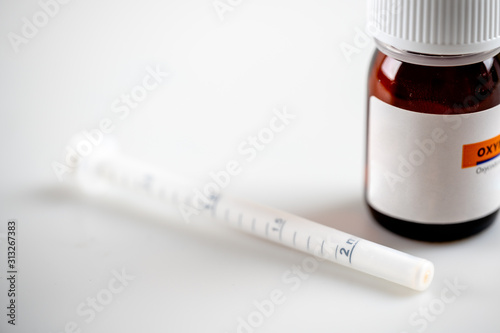 macro shot of liquid oxycodone bottle and oral medication syringe photo