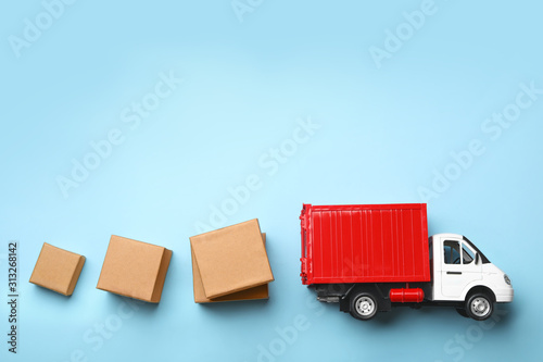 Top view of toy truck with boxes on blue background. Logistics and wholesale concept