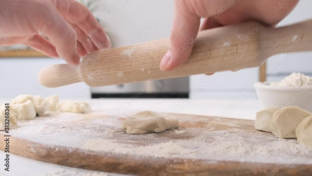 Man rolls dough with rolling pin on wooden chopping board. Close up. Man rolls dough with rolling pin on wooden chopping board. Close up.