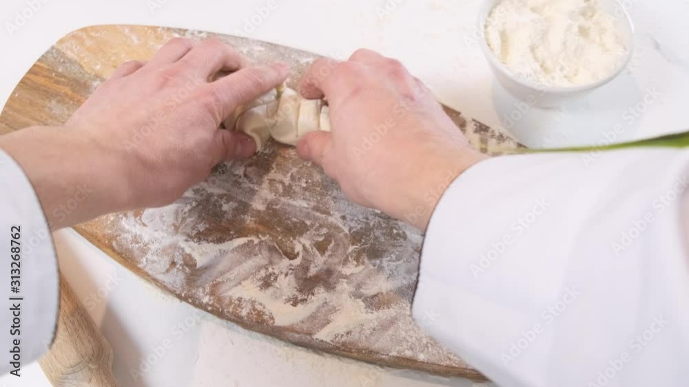 Man rolls dough with rolling pin on wooden chopping board. Close up. Man rolls dough with rolling pin on wooden chopping board. Close up.