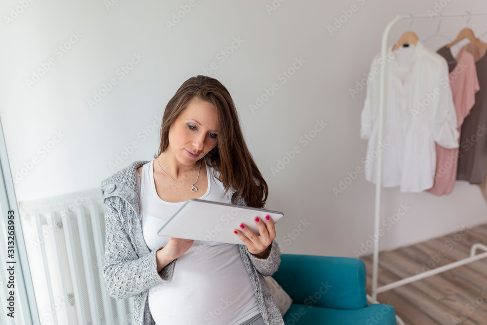 Pregnant woman surfing the new on tablet computer Pregnant woman surfing the new on tablet computer