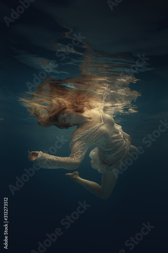 Girl in a beautiful dress swims underwater
