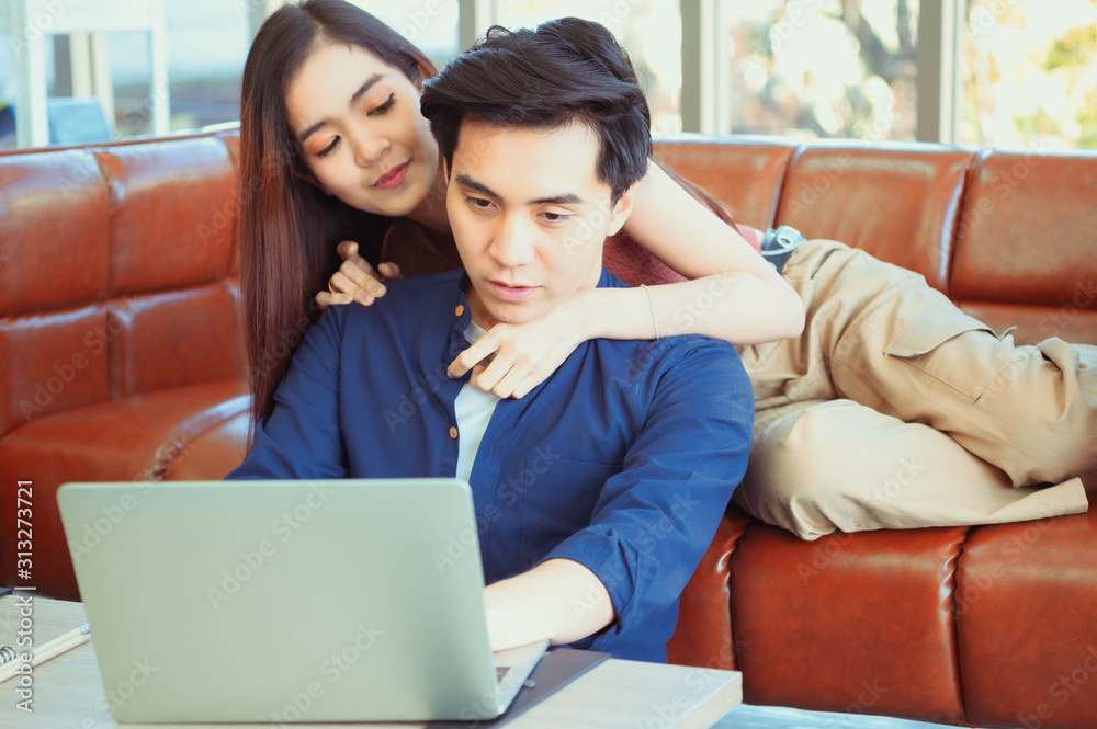 Excited young couple looking at laptop. Young couple watching media content online in a tablet sitting on a sofa in the living room.