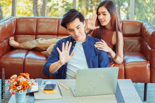 Happy Asian Lover or couple talking and smiling when using technology laptop on the bed in bed room at modern home, young woman pointing to the forehead of boyfriend, Lover concept.  © Ha-nu-man